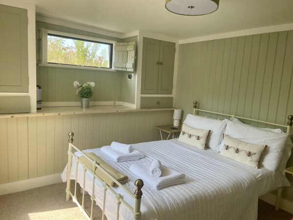 Un dormitorio ordenado con cama, mesitas de noche, una ventana y armarios empotrados.