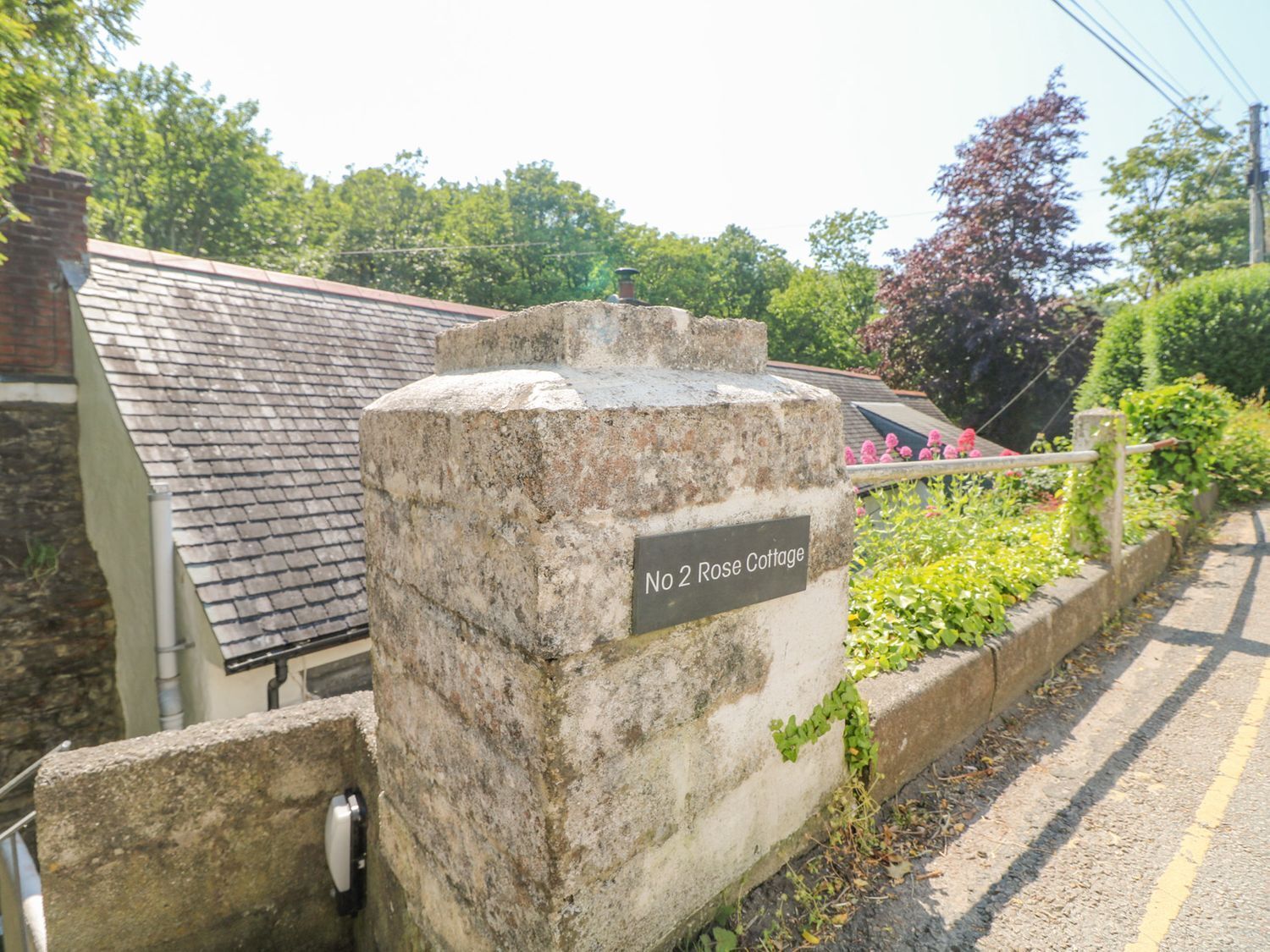 A stone wall with a sign reading "No 2 Rose Cottage."