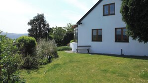 A white house with a sloped roof, a garden, and a bench. - Artist's Cottage (Penrhyndeudraeth)