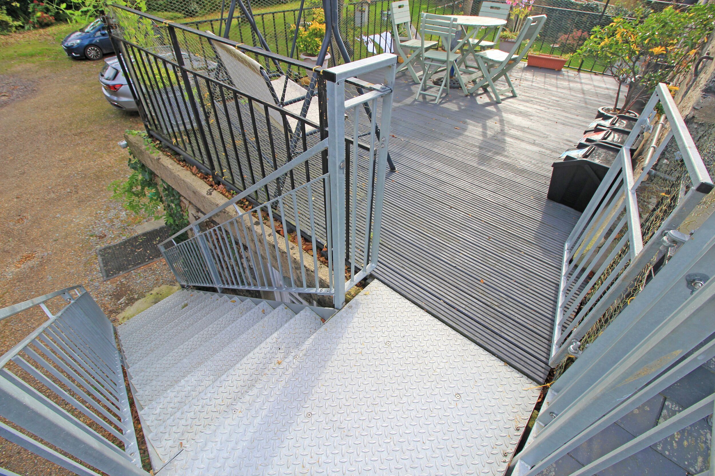 A metal staircase leading to a deck area with outdoor furniture.