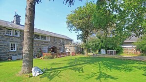 A stone building with a large lawn, a tree, and a small shed. - Treetops Flat (Porthmadog)