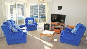 A living room with two blue armchairs, a wooden coffee table, and a television on a wooden stand. - Glaslyn Harbour Views (Porthmadog)