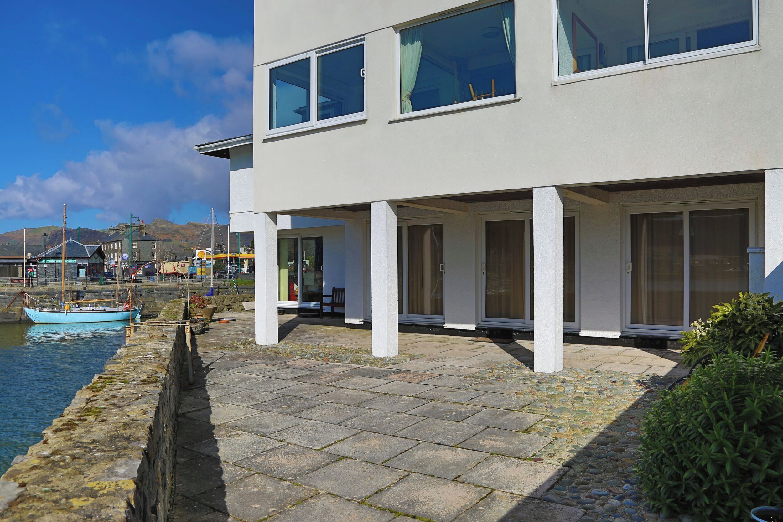 A modern building with large windows and a stone pathway leading to a dock.