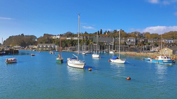 A harbor with boats docked, a clear sky, and buildings in the background. - Glaslyn Harbour Views (Porthmadog)