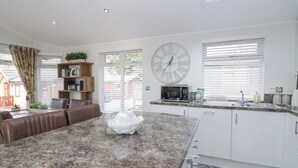 A modern kitchen with a granite countertop, white cabinetry, and a large wall clock. - Swifts Reach Lodge (Windermere)