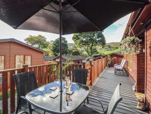 Une terrasse extérieure avec une table et des chaises, un grand parasol et une vue sur le paysage environnant.