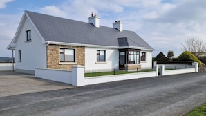 Une maison à deux étages avec une façade en pierre, un toit gris et une clôture noire.