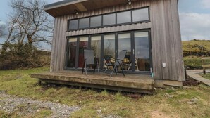 A modern two-story building with large windows and a wooden deck. - Tirlaggan Studio (Oban)