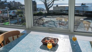 Et bord med en blomstret dug, en kurv med croissanter og et glas appelsinjuice.