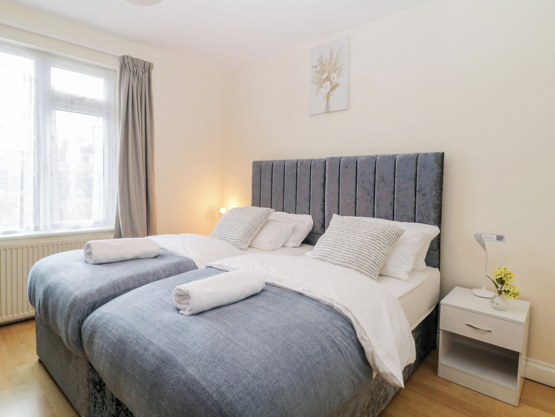 Een moderne slaapkamer met een groot bed, twee nachtkastjes, een venster met gordijnen.