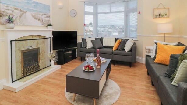 A living room with a fireplace, a sofa set, a coffee table, and a television. - Hilltop Cottage (Paignton)