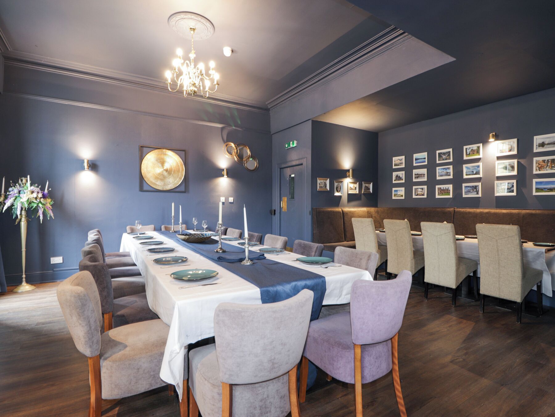 A dining area with a long table set for a meal, surrounded by upholstered chairs.