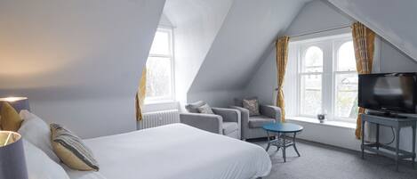 Une chambre d’hôtel moderne avec un grand lit, un petit canapé, une télévision et une fenêtre avec des rideaux.
