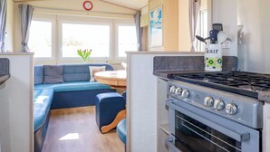 Eine kompakte Küche mit Herd, Backofen und einer Essecke mit blauem Sofa und Tisch.
