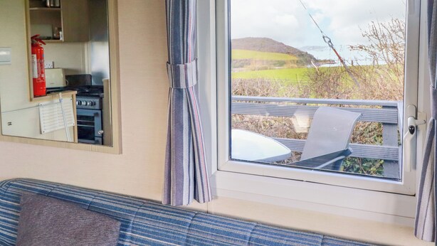 Ein Zimmer mit einer Küchenzeile, einem Sofa und einem großen Fenster mit Blick auf eine grüne Landschaft.