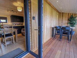 Una cocina moderna con paneles de madera, una zona de comedor con mesa y sillas, y una planta grande en maceta.