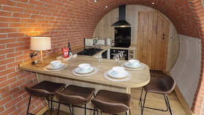 A compact kitchen with a brick arch ceiling, a central island with bar stools, and modern appliances. - Weirglodd (Ruthin)