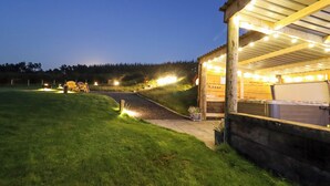 A building with a covered outdoor area, a paved path, and a grassy field. - Weirglodd (Ruthin)
