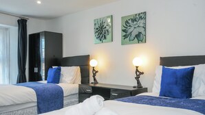 Une chambre d’hôtel avec deux lits, une table de chevet, une armoire et des œuvres d’art accrochées au mur.