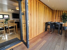 Una cocina moderna con paneles de madera, un comedor con sillas y mesa de madera, y una planta en maceta.
