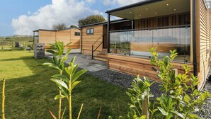 A modern wooden building with large windows and a covered patio area.
