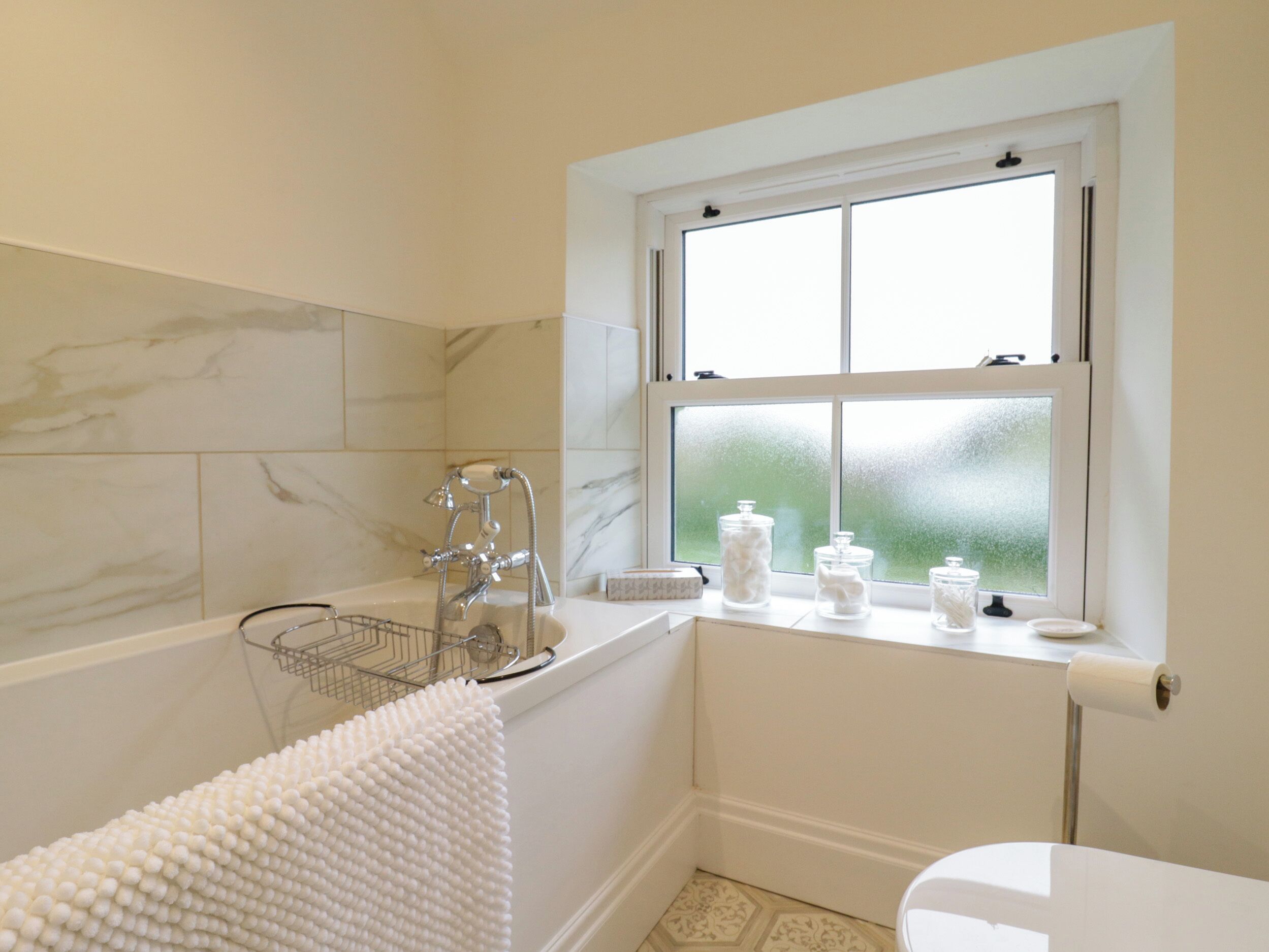 Une salle de bain avec une baignoire, une fenêtre et des toilettes.