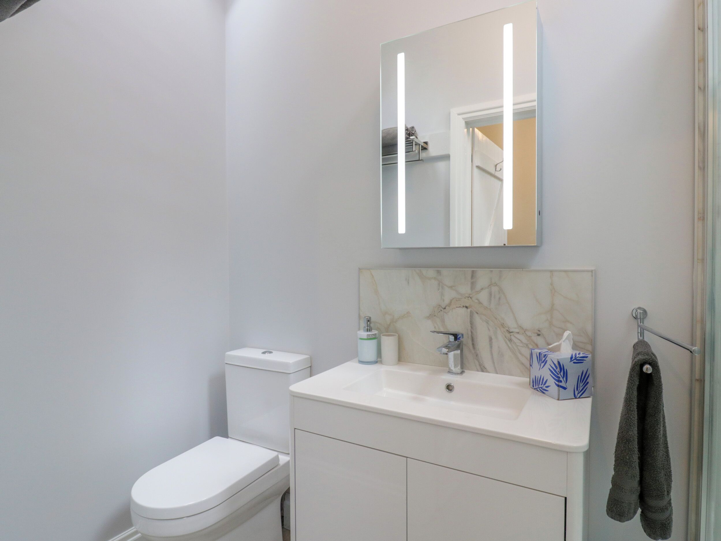 Un baño con inodoro, lavamanos y espejo.