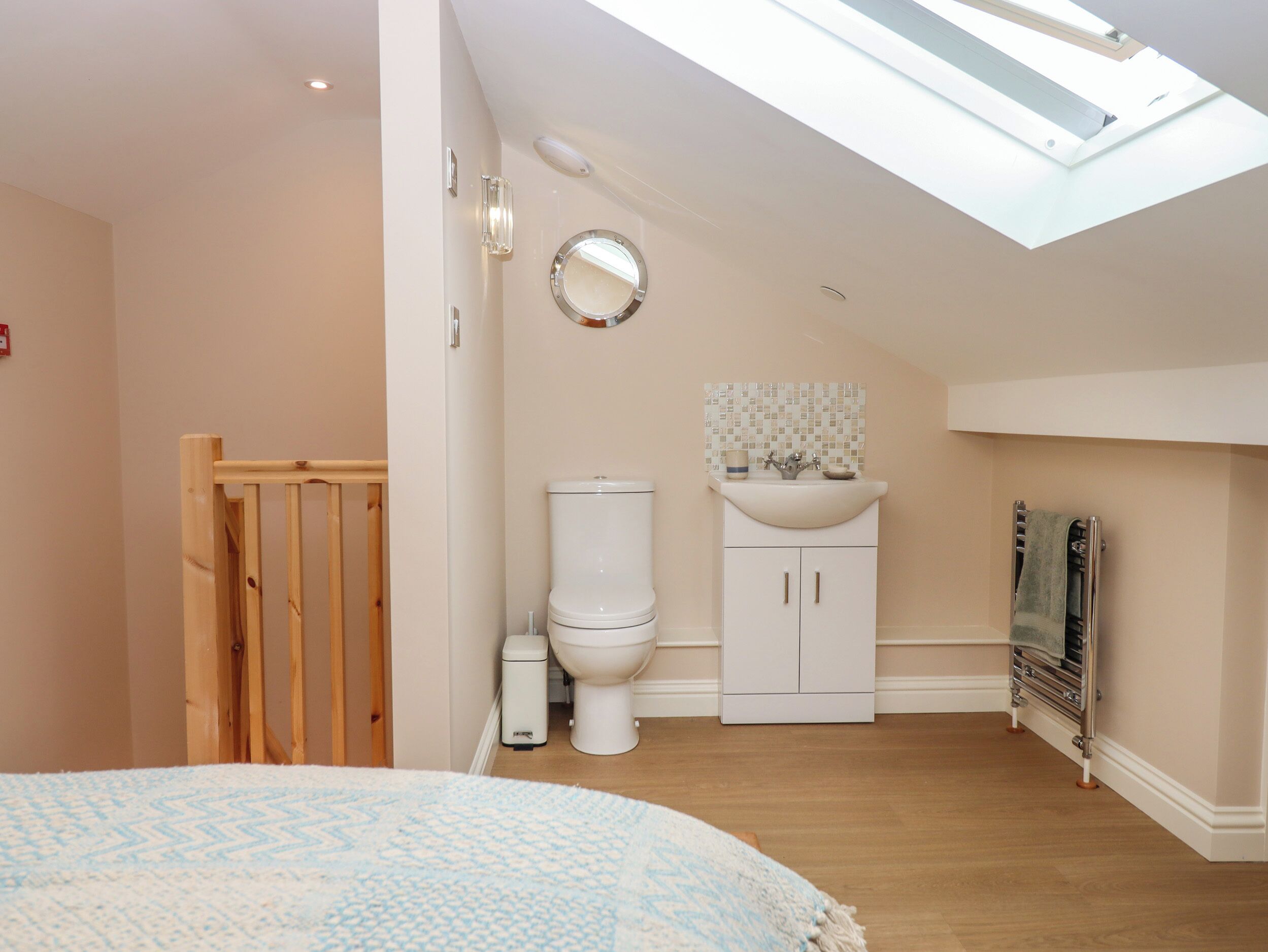 A bedroom with a skylight, a wooden door, a white toilet, a sink, and a towel rack.