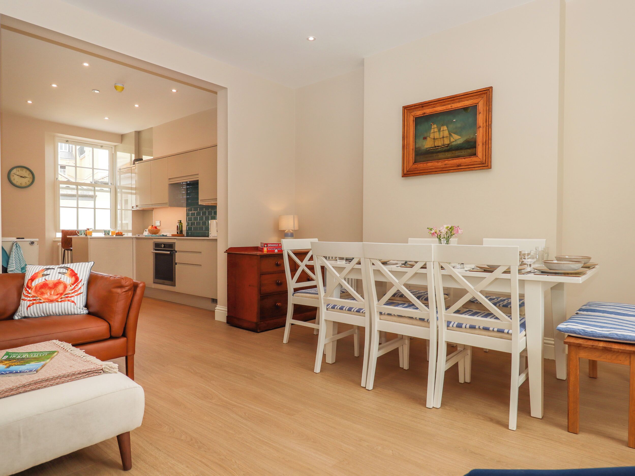 A cozy living room with a dining area, a kitchen in the background, and a painting on the wall.