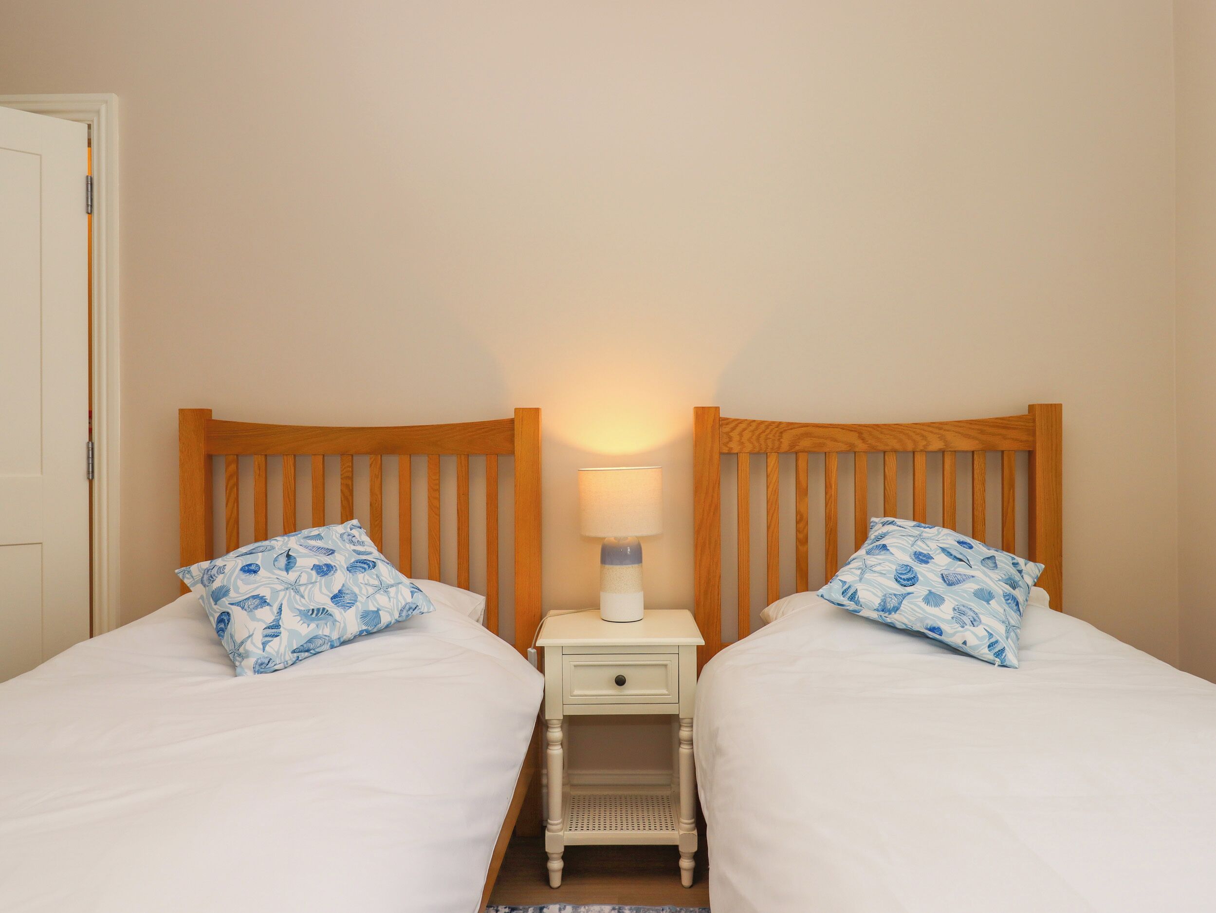 A double room with two beds, each with a wooden headboard and a white nightstand between them.