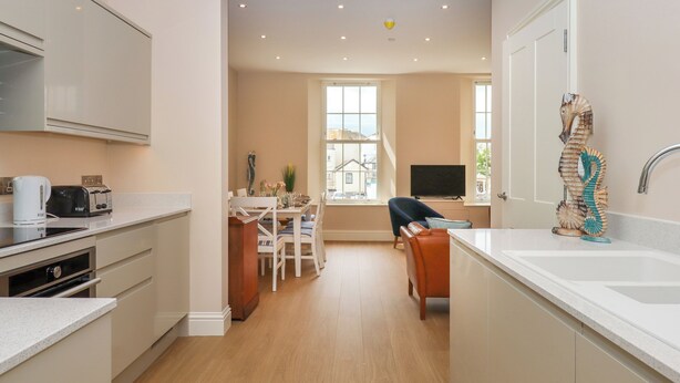 A modern kitchen with a dining area, a TV, and a unique seahorse sculpture. - 2 Sea Otter House (Teignmouth)