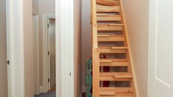 Una escalera de madera en un pasillo con paredes y puertas blancas.