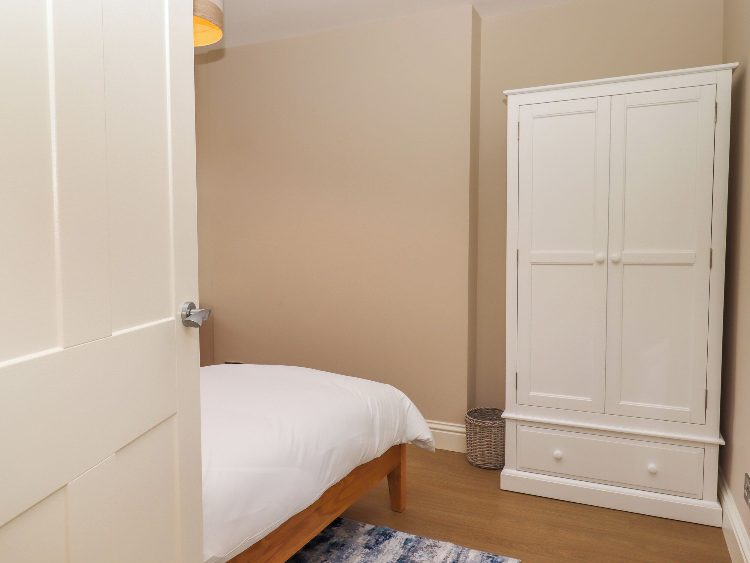 A bedroom with a bed, a wardrobe, and a small rug.