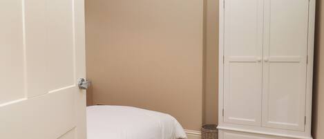 A bedroom with a bed, a wardrobe, and a small rug.