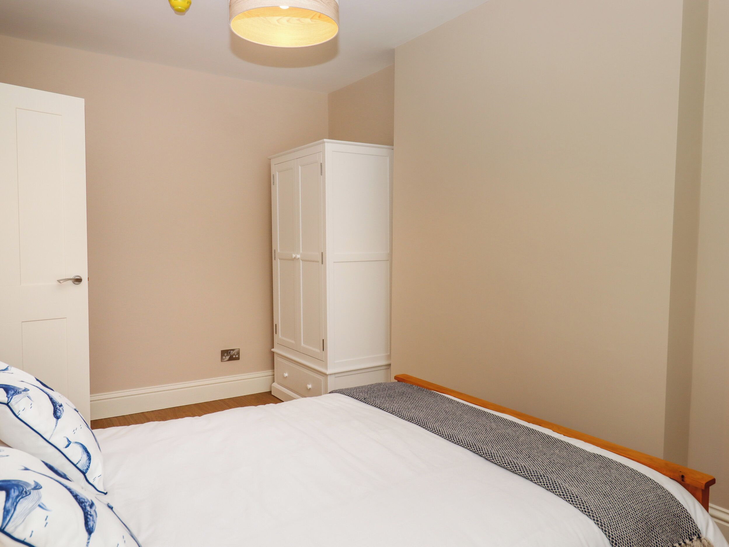 A bedroom with a bed, a wardrobe, and a light fixture.