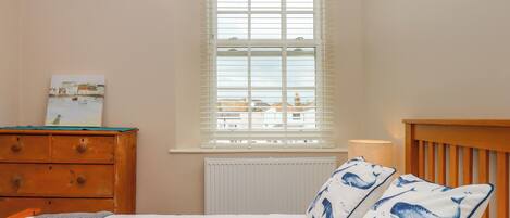 Un dormitorio con cama, cómoda de madera y ventana con persianas.