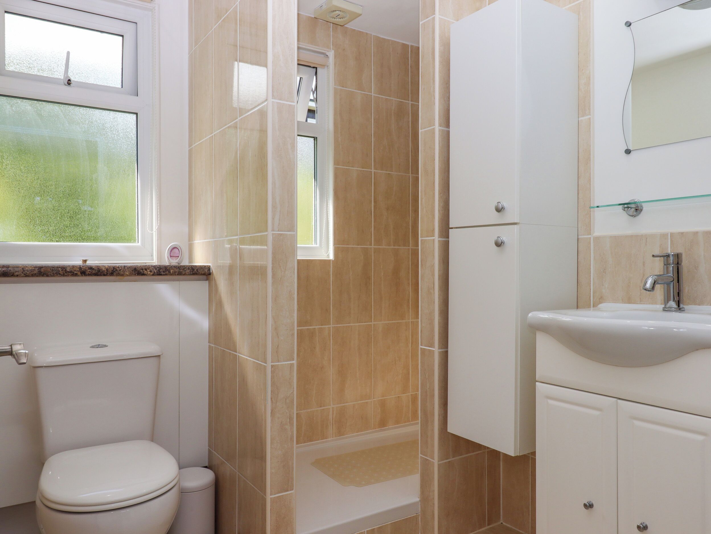 A bathroom with a toilet, shower, and sink.