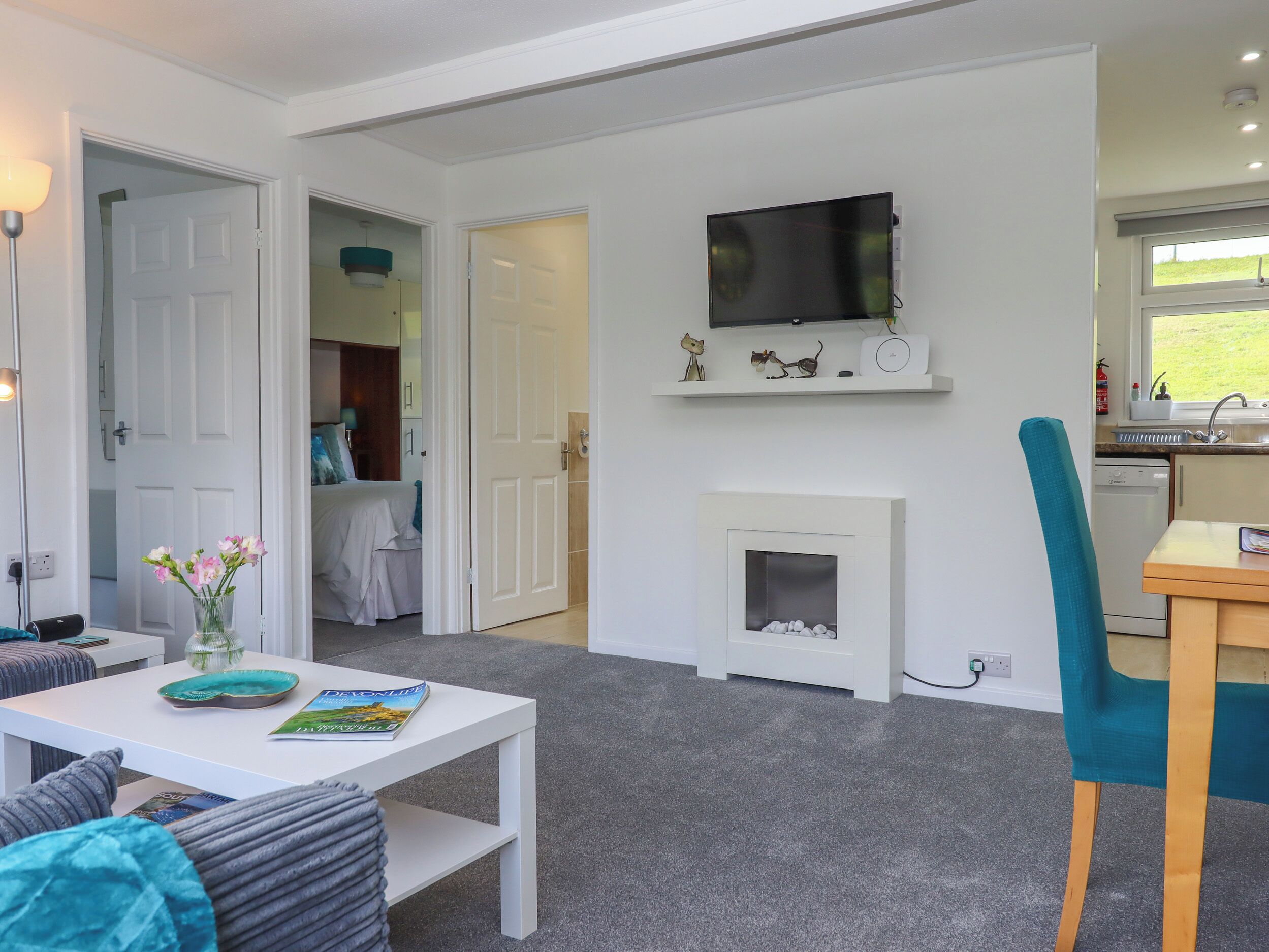 A modern living room with a fireplace, a television mounted above it, and a dining area with a table and chairs.