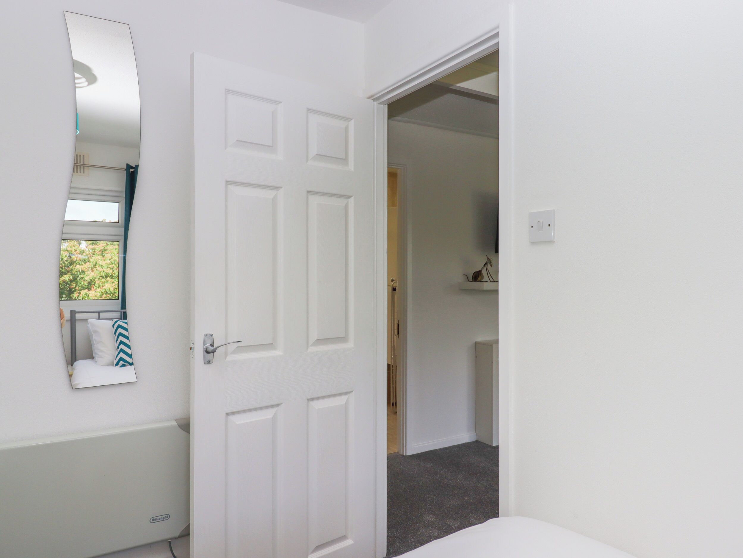 Une salle de bain blanche avec un miroir, une porte et un espace douche.