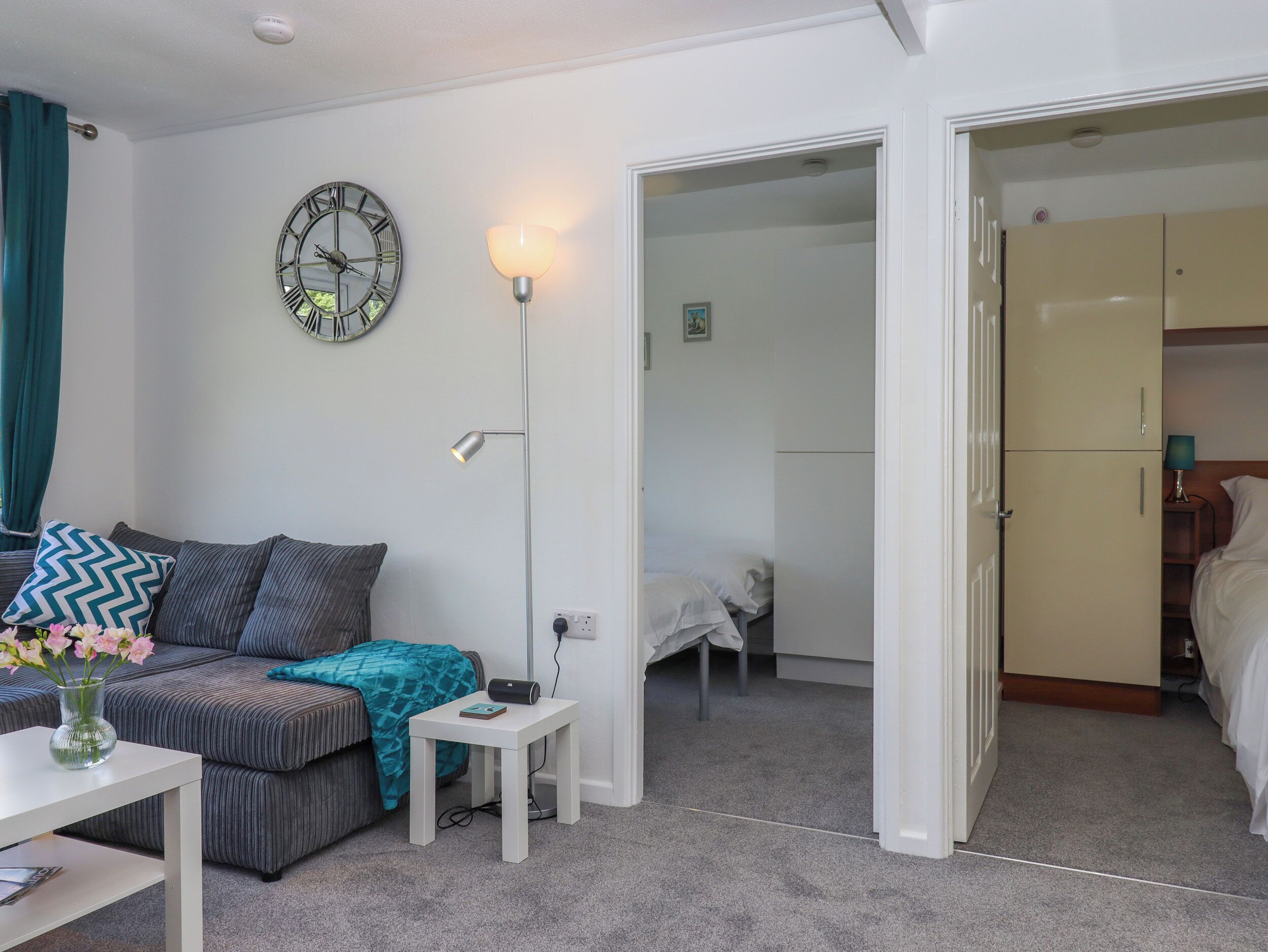 Una habitación moderna con sofá, una mesita con un florero, lámpara y armario.