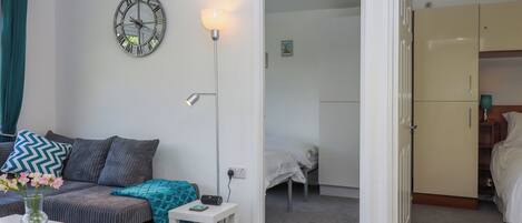 Una habitación moderna con sofá, una mesita con un florero, lámpara y armario.