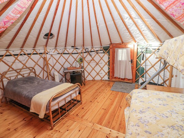 A cozy yurt with a bed, a small table with a kettle, and a wooden chair. - Blaidd Bach (Carmarthen)