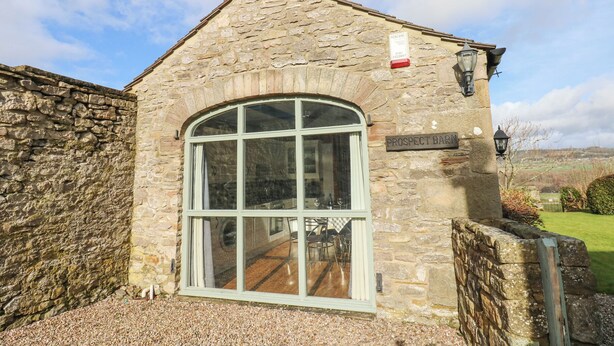 Un bâtiment en pierre doté d’une grande fenêtre en arc de cercle et d’une enseigne indiquant « Prospect Barn ».