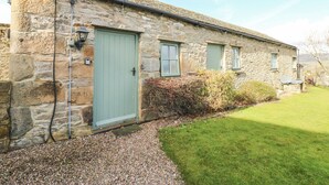 Un bâtiment en pierre avec une porte verte, des fenêtres et une allée gravillonnée.