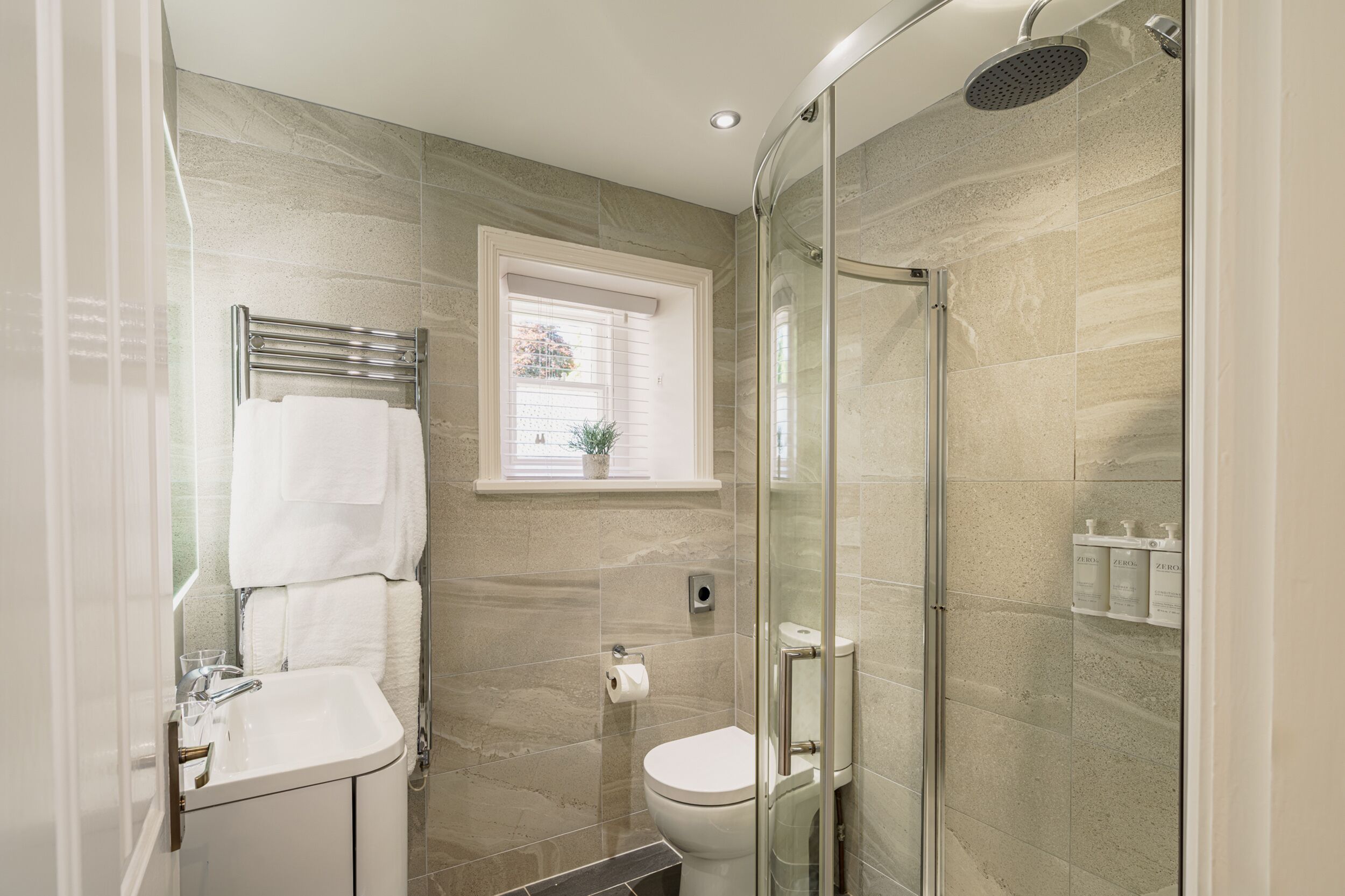 A modern bathroom with a glass-enclosed shower, a toilet, and a sink.