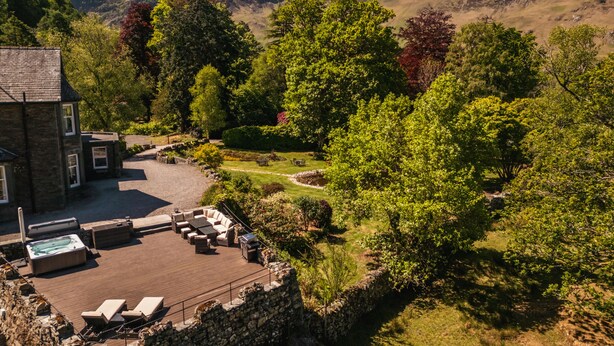 A stone house with a wooden deck, outdoor seating, and a hot tub. - Leathes Head Country House (Keswick)