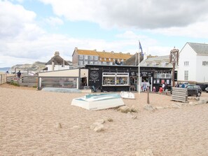 A coastal building with a beachside view, featuring a cafe, a lobster restaurant, and a visible entrance. - Seagulls Nest (Bridport)