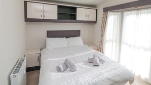 Habitación de hotel con cama, armario empotrado, radiador y ventana con cortinas.