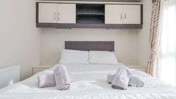 A hotel room with a bed, two nightstands, a wardrobe, and a window with curtains.