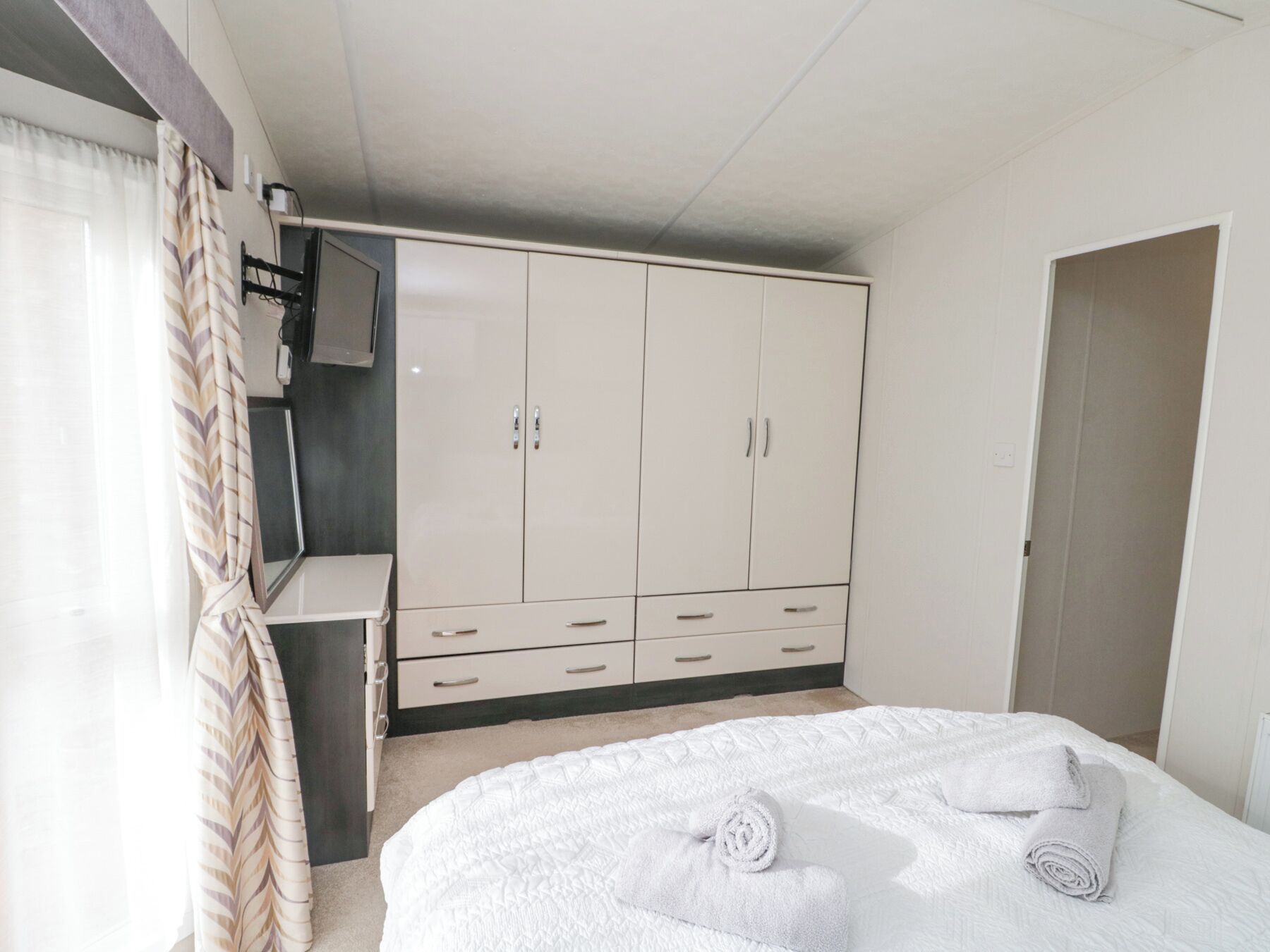 A bedroom with a bed, a wardrobe, and a television.